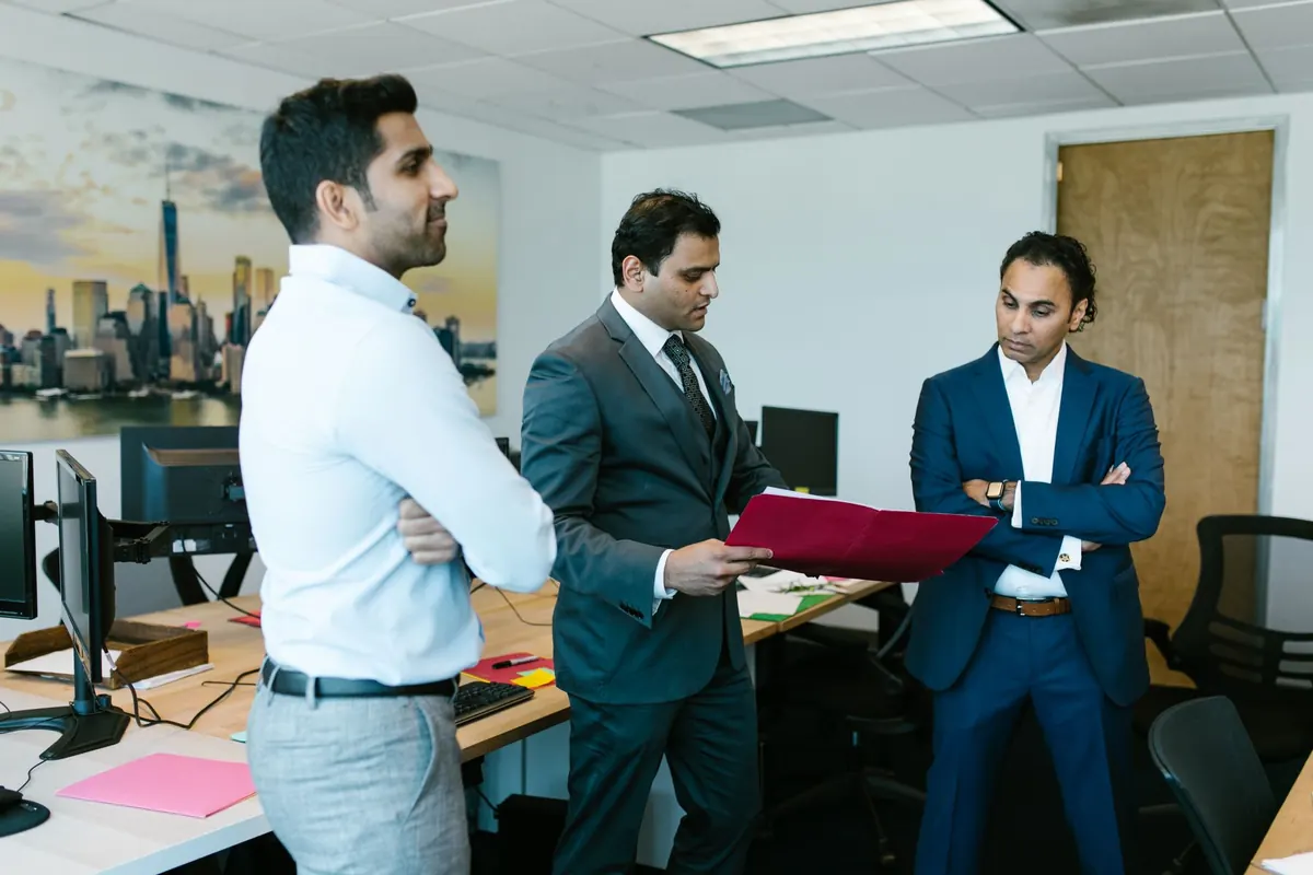 Three colleagues reviewing candidate documents at an office desk